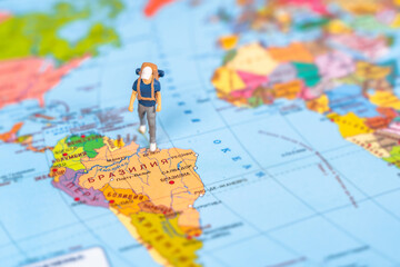 Miniature figure of a traveler with a backpack on the world map, map in Russian. Selective focus