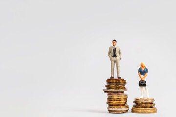 Miniature successful businessmen are standing on stacks of coins. A man and a woman in business,...