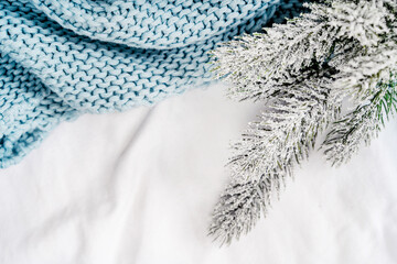 Cozy winter concept with a spruce twig on a bed with a white sheet and a blanket. Christmas Morning