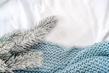 Cozy winter concept with a spruce twig on a bed with a white sheet and a blanket. Christmas Morning