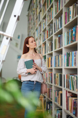 Woman choosing books near bookshelves in library