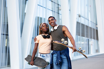 Beautiful African couple having fun outdoors. Portrait of an excited young couple with skateboard..