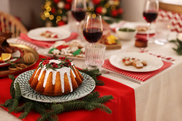 Festive dinner with delicious cake served on table indoors, space for text. Christmas Eve celebration
