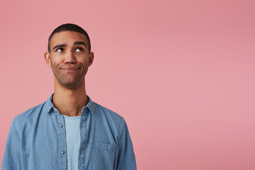 studio portrait of middle age middle eastern man wears blue shirt confused looking aside at copy space. isolated over pink background