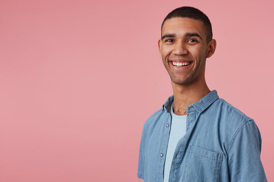 studio portrait of middle age middle eastern man wears blue shirt smiles broadly and feels happy. isolated over pink background