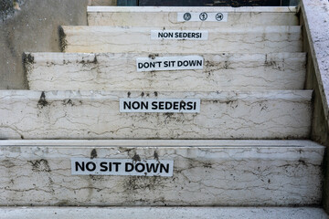 Warning signs on marble steps in Venice: Don't sit down, Non sedersi