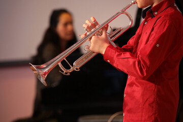 Person playing the trumpet blowing into a silver musical instrument in red clothes close-up in the...