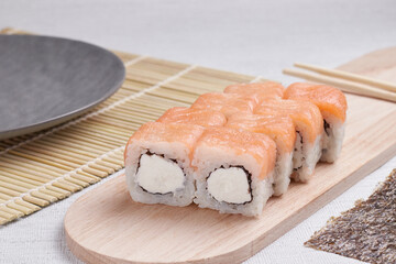 a portion of rolls on a stand, japanese food, sushi on the table, chinese chopsticks, light background