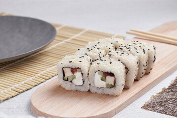 a portion of rolls on a stand, japanese food, sushi on the table, chinese chopsticks, light background