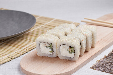 a portion of rolls on a stand, japanese food, sushi on the table, chinese chopsticks, light background