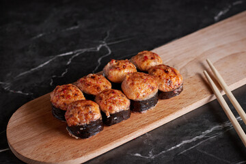 a portion of rolls on a stand, japanese food, sushi on the table, chinese chopsticks, dark background