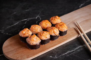 a portion of rolls on a stand, japanese food, sushi on the table, chinese chopsticks, dark background