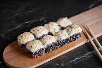 a portion of rolls on a stand, japanese food, sushi on the table, chinese chopsticks, dark background