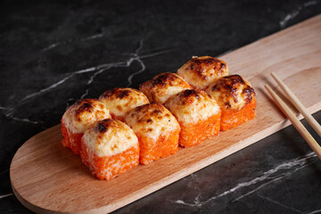 a portion of rolls on a stand, japanese food, sushi on the table, chinese chopsticks, dark background