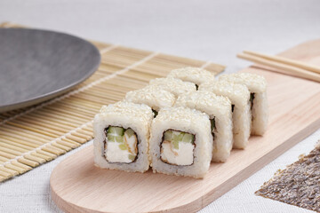 a portion of rolls on a stand, japanese food, sushi on the table, chinese chopsticks, light background