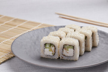 a portion of rolls on a stand, japanese food, sushi on the table, chinese chopsticks, light background