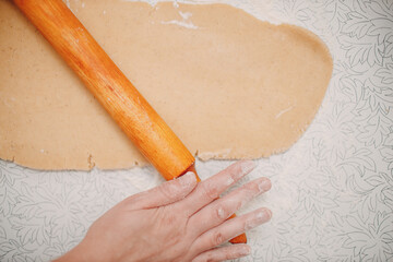Pastry chef rolls out dough with rolling pin and makes delicious ginger cookies. Cooking and decorating christmas dessert.