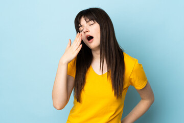Fototapeta premium Teenager Ukrainian girl isolated on blue background yawning and covering wide open mouth with hand