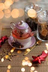 Obraz na płótnie Canvas Beautiful white and lilac teapot with a mix of teas in the background and red liquid tea inside