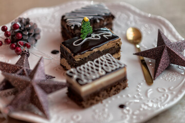 Variety of delicious sweet chocolate and coffee cakes on a white plate with a golden spoon