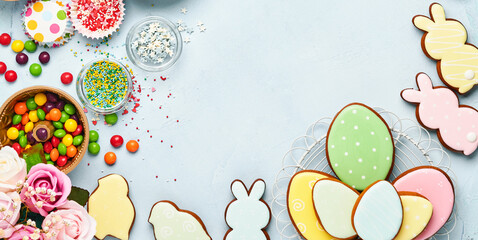 Easter baking background. Easter multicolored gingerbread, candy and confectionery topping dressing on blue background. Celebratory background concept. Space for text.