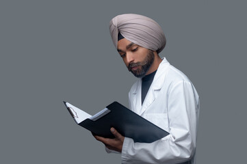 Handsome focused male doctor scrutinizing his patient files
