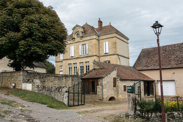 Fototapeta na wymiar former school with walled schoolyard and chestnut tree and houses in the little Brionnais village of Vareilles