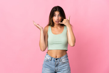 Young caucasian woman isolated on pink background making phone gesture and doubting