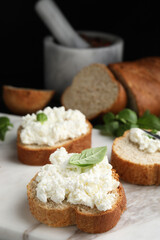 Bread with cottage cheese and basil on board, closeup