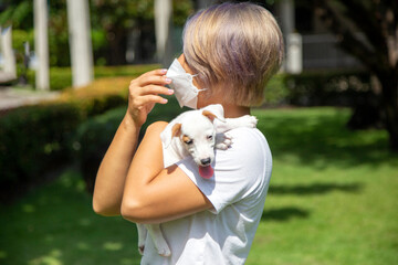 Woman wearing protective mask hug with a dog at park