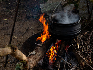 camp kitchen with cauldron, open steaming hot, metal on fire