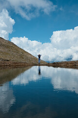 Fototapeta premium a girl on the edge of a lake, a mountain lake from a glacier, a shadow and a blue sky, a reflection in the water of clouds