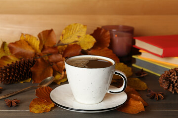 Composition with cup of hot coffee and autumn leaves on wooden table