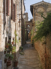 typical medieval street of Colle di Val d'Elsa along the perimeter of the village with the ancient buildings built by stones on a side and the city walls on the other