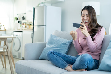 Asian young beautiful woman playing mobile game on smartphone at home. 