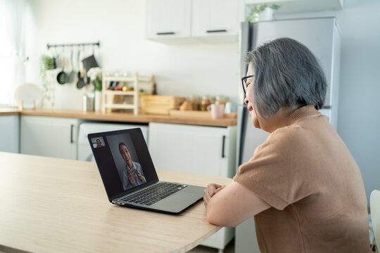 Asian senior older woman video call with doctor in living room at home