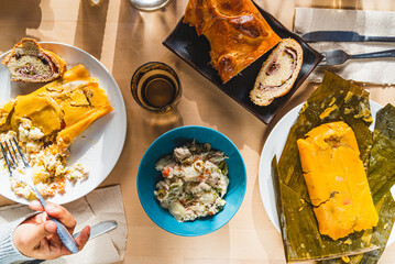 venezuelan christmas food display on table with traditional hallacas, pan de jamon or ham bread, and mixed salad, with cutlery and ready. traditional dishes of venezuelan cuisine