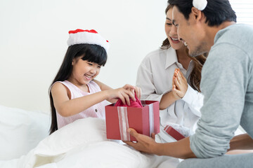 Asian lovely young little daughter open present gift box from parents.