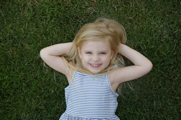 Fototapeta premium Portrait of cute little girl laying on the grass