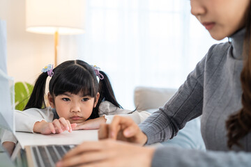 Asian young kid daughter feeling sad and need to play with busy mother