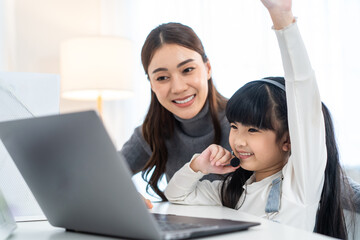 Asian little young girl kid learning online class at home with mother. 