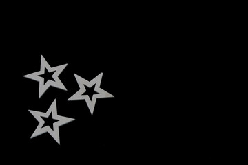 Three white wooden stars isolated on black background with copy space