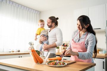 Caucasian beautiful parents cook food with baby boy toddler in kitchen
