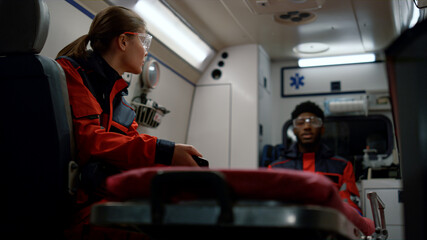 Medical team talking about work in emergency vehicle. Doctors driving on call
