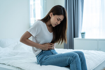 Asian beautiful sick girl in pajamas getting up from sleep in bedroom. 