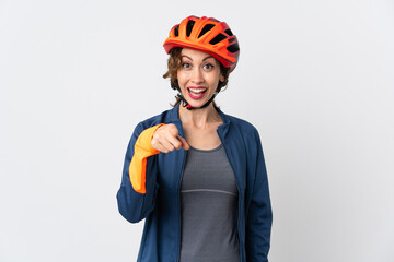 Young cyclist woman isolated on white background surprised and pointing front