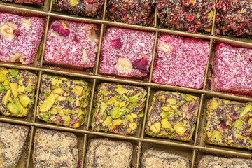 assortment of traditional Turkish delight (lokum) in a tin box against handmade paper with a copy space, soft, juicy, and chewy dessert from the middle east