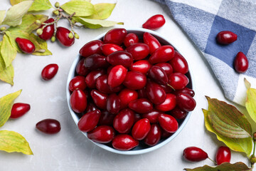 Fresh ripe dogwood berries, leaves and napkin on light grey table, flat lay