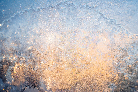 The texture of the glass covered with frost in winter in cold. Magical winter patterns on the glass. Natural phenomena. Frozen water on the window.
