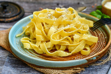 Italian food . Fresh home made  tagliatelle vegetarian  egg pasta  with ,parmesan cheese ,fresh parsley  and black pepper.Pasta cacio e pepe